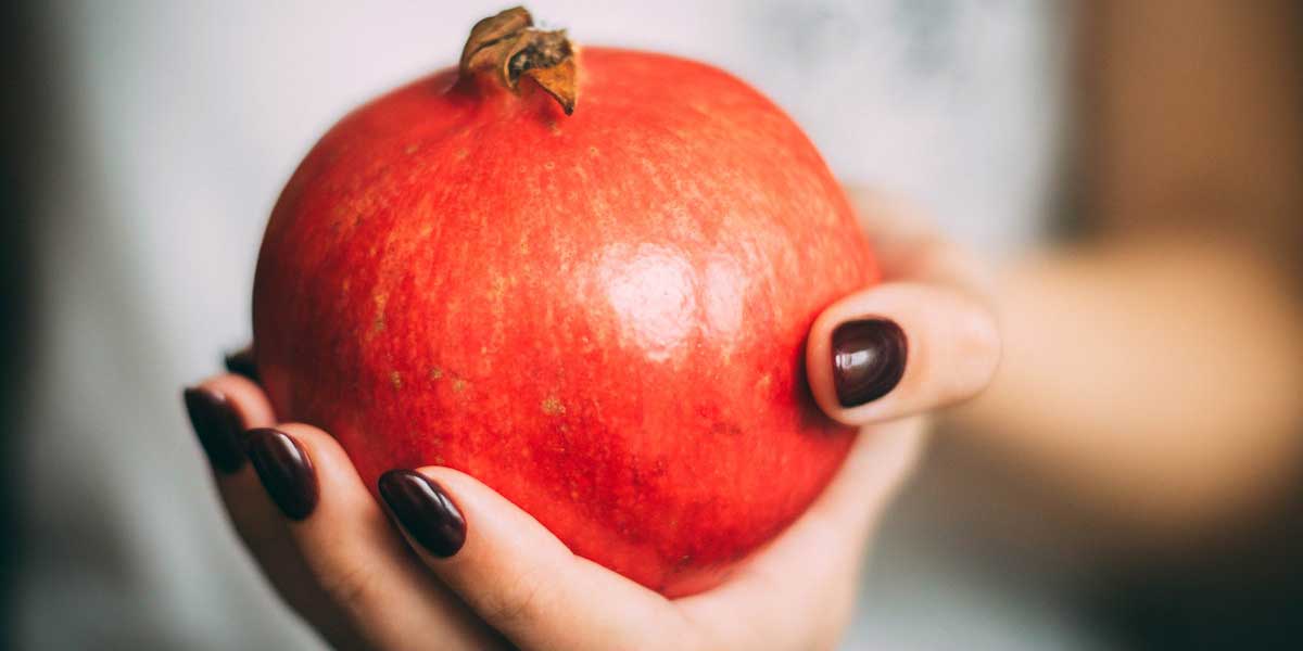 A ripe pomegranate fruit on a human hand.