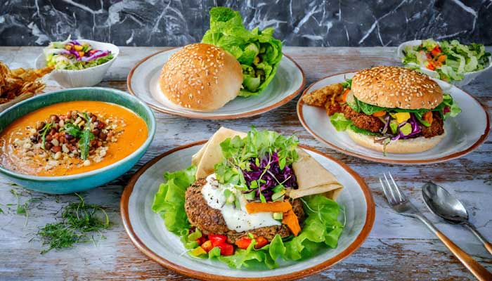 Four plates with diverse Bibb lettuce recipes: salad, wrap, soup, vegan burger.